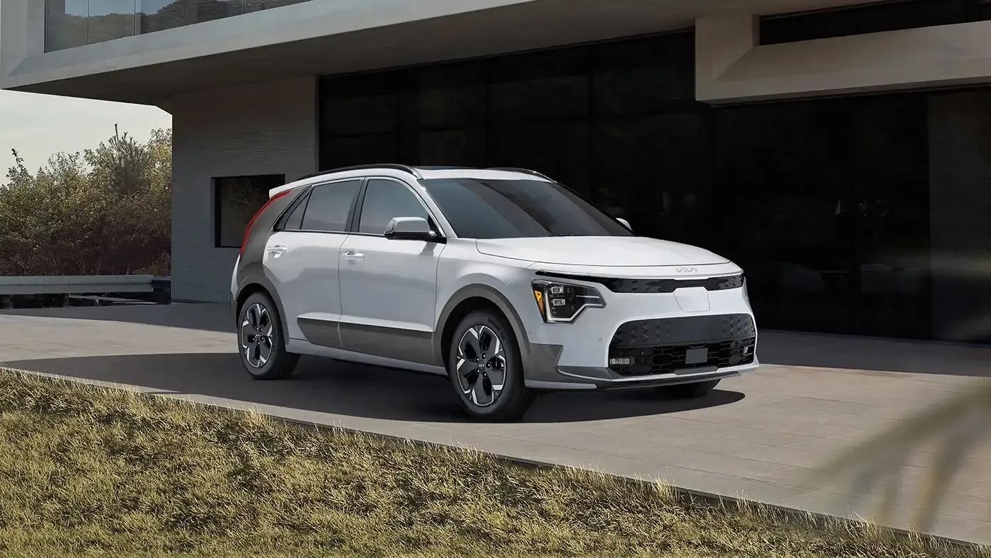 Kia Niro EV 2025 garé devant une résidence moderne, mettant en valeur son design compact et son style urbain.